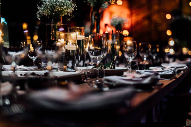 Luxury table settings for fine dining with and glassware, pouring wine to glass. Beautiful blurred background. Preparation for holiday wedding. Fancy luxury restaurant.